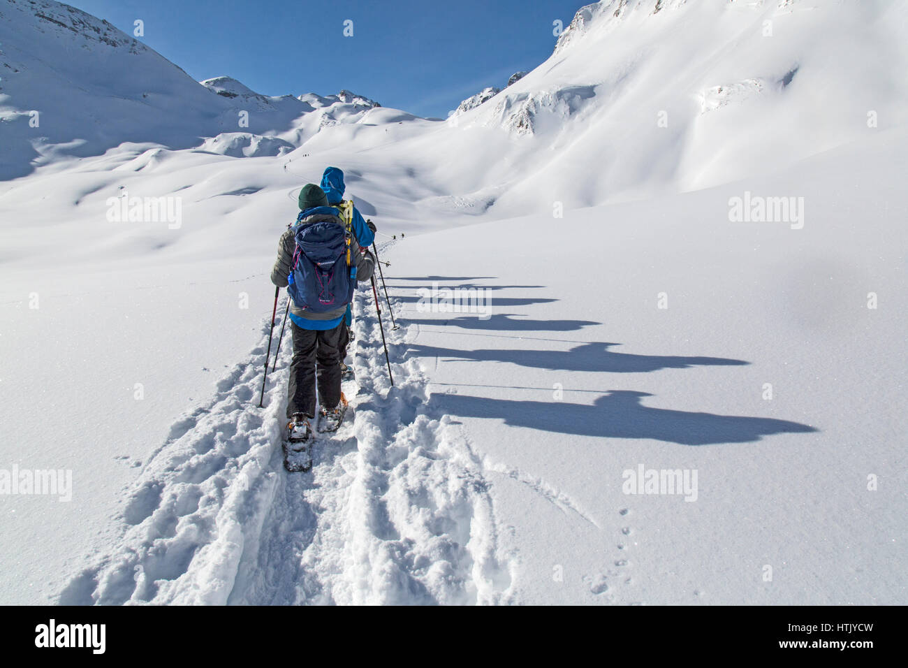 Le persone con le racchette da neve nelle Alpi austriache con le loro ombre proiettate nella neve. Foto Stock