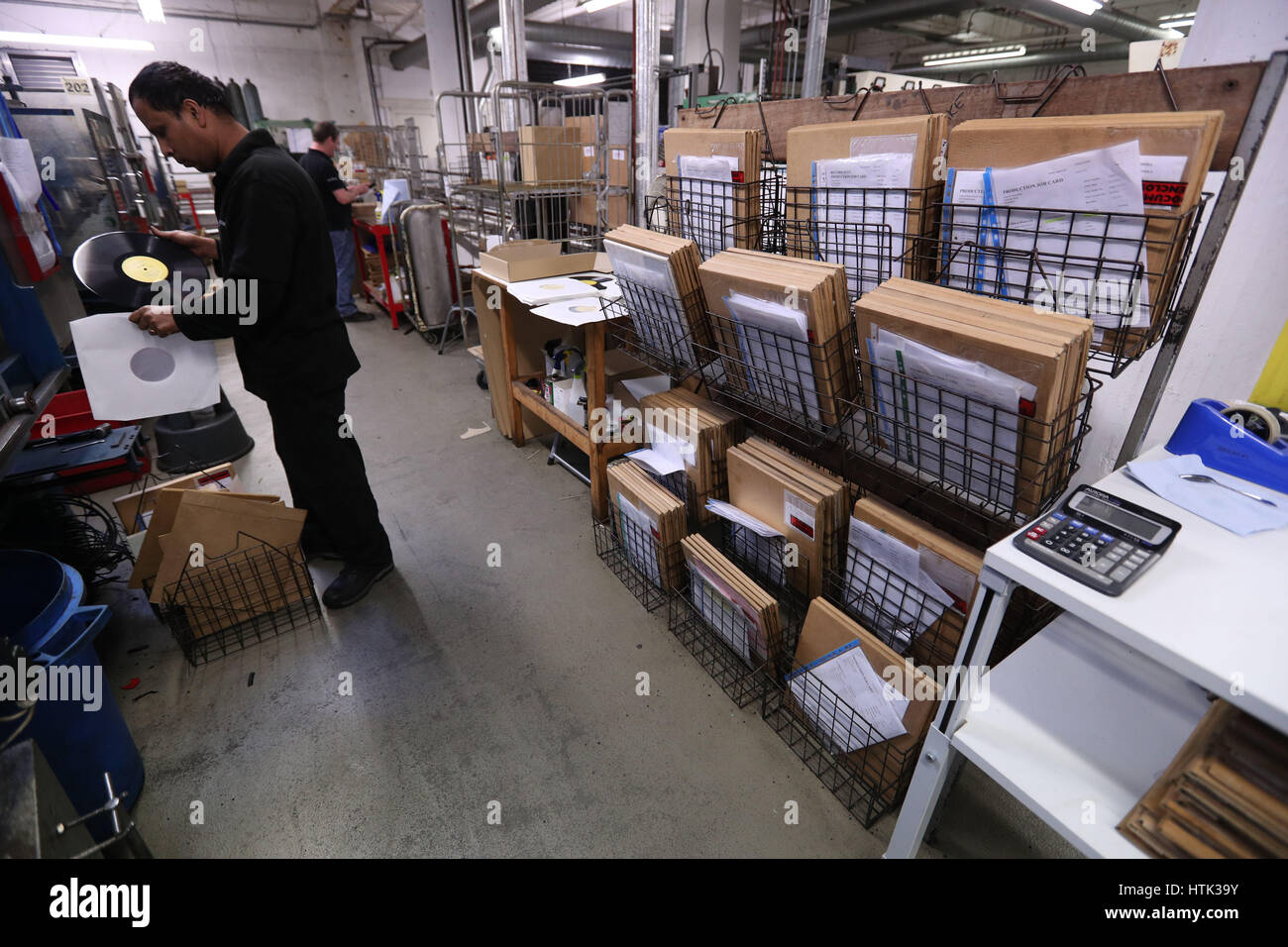 Un ingegnere esegue controlli di qualità in tra il vinile premere e una raccolta degli ordini di produzione presso la fabbrica di vinile, Hayes, Middlesex. Foto Stock