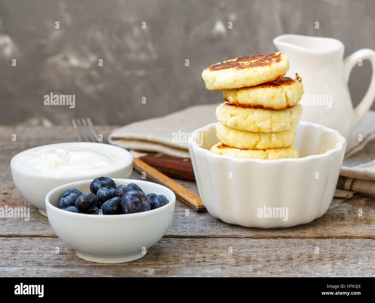 Cottage cheese pancakes per colazione con mirtilli e panna acida. Foto Stock
