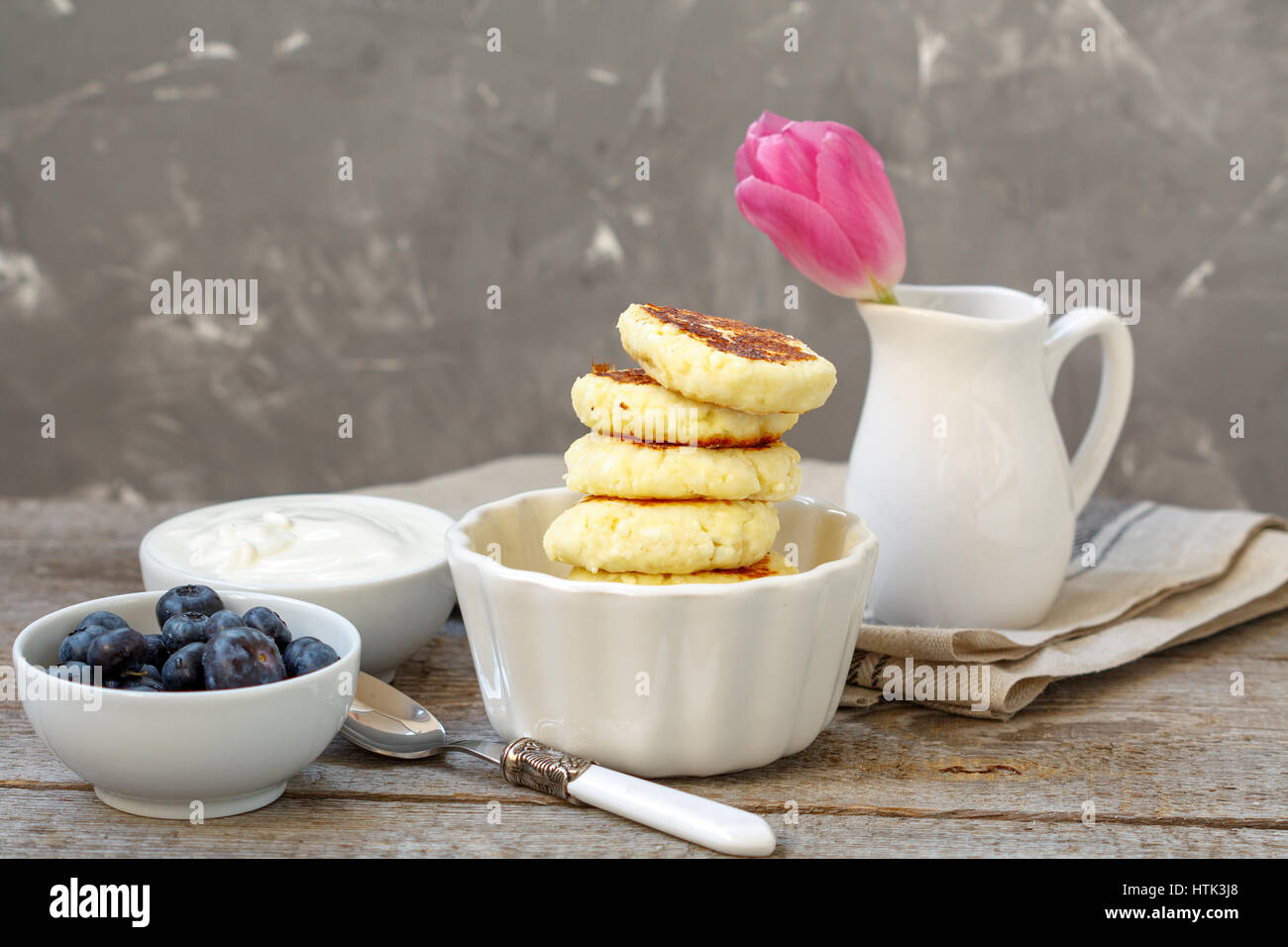 Cottage cheese pancakes per colazione con mirtilli e panna acida. Foto Stock