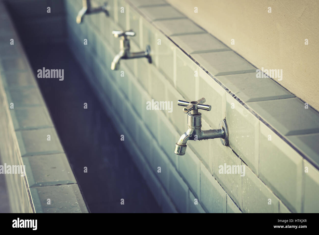 Fila di rubinetti di acciaio in una grande stanza da bagno Foto Stock