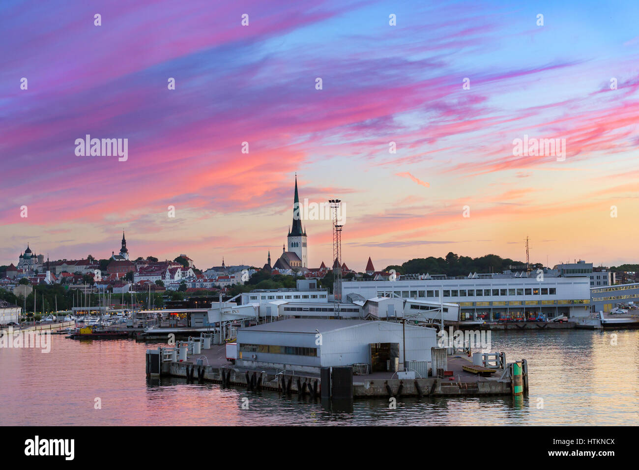 Serata panorama di Tallinn al tramonto. Vista dal traghetto sul terminale marittimo del porto passeggeri e la città vecchia architettura con alta guglia sulla chiesa di San Olaf. Foto Stock