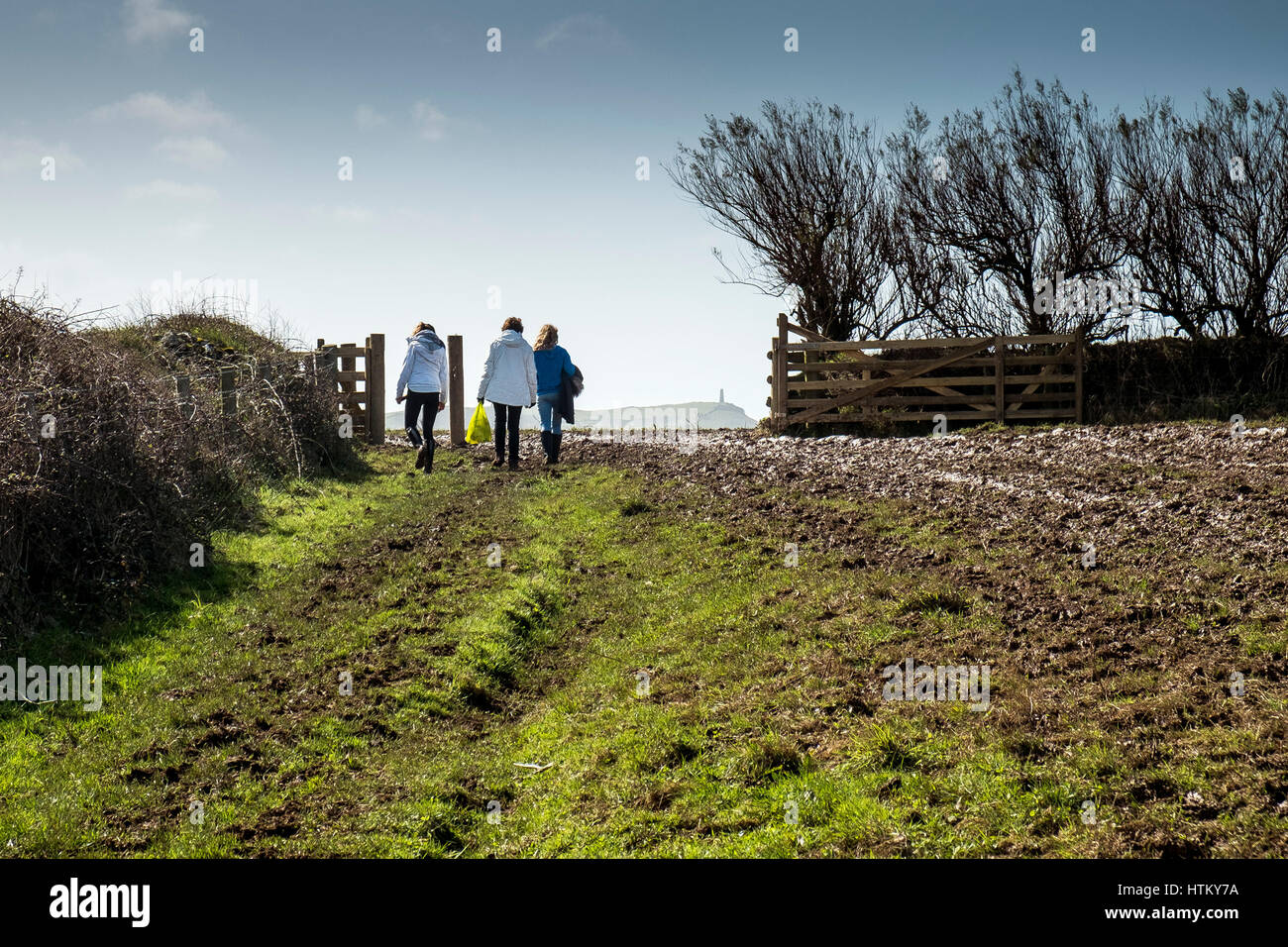 Tre persone a piedi campo gate Pentire Headland Cornovaglia Foto Stock