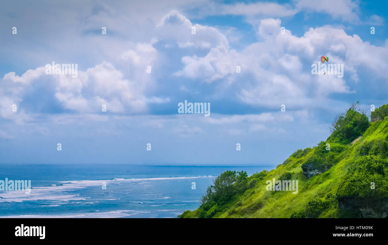 Parapendio volare le colline erbose sopra Gunung Payung spiaggia nella zona nord-est di Bali una delle famose zone per il parapendio Foto Stock