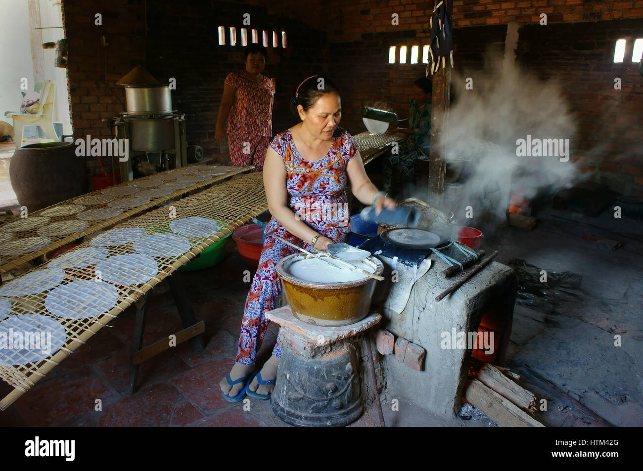 Ba Ria, Viet Nam, donna asiatica seduta di lavoro a casa, Vietnamita femmina di rendere la carta di riso da farina di riso a banh trang trade village, Vietnam Foto Stock