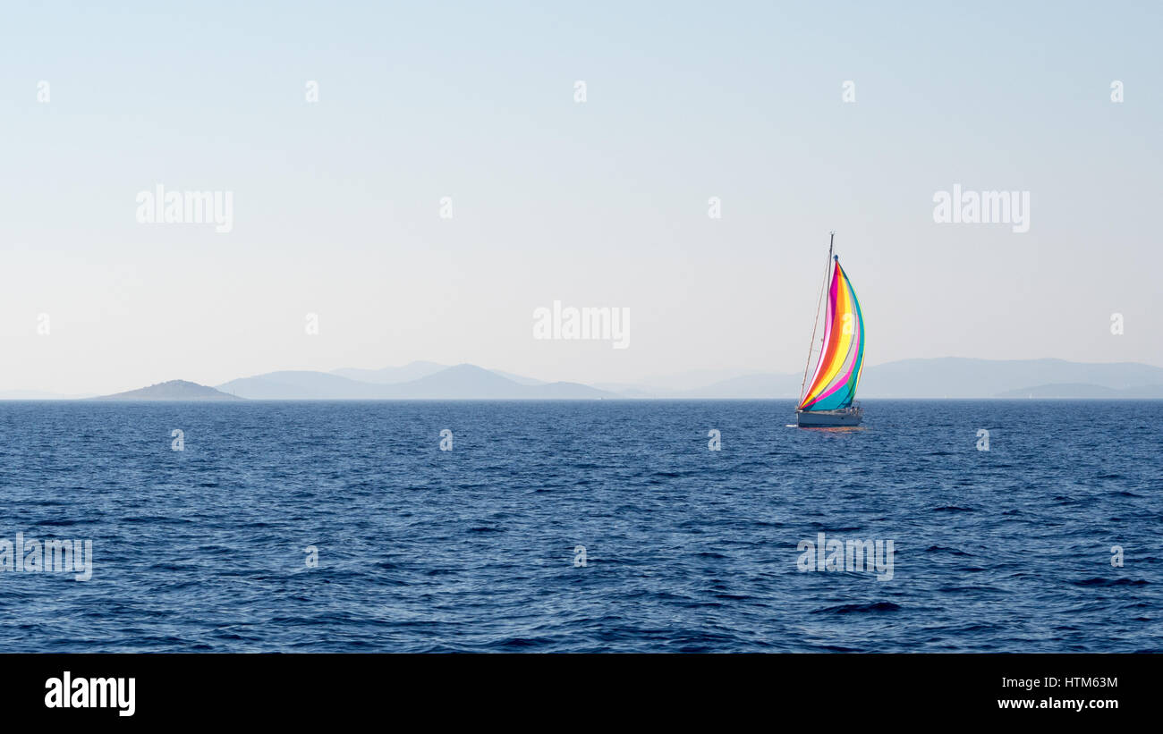 Uno yacht a vela barca con multicolore multicolore vele vela vela sul mare Mediterraneo oceano blu cielo sulle calme acque al largo della costa della Croazia Foto Stock