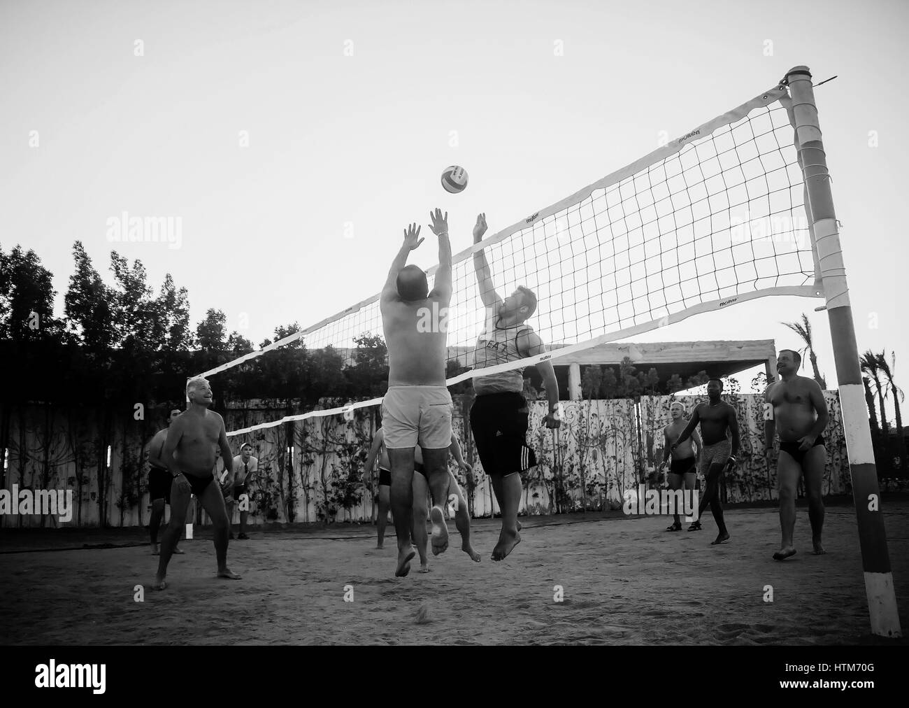 Voce maschile caucasici, gli Arabi, gli africani e giocando a pallavolo sulla spiaggia al tramonto. L'Egitto. Hurghada. Golden 5 Ottobre 7, 2016 Foto Stock