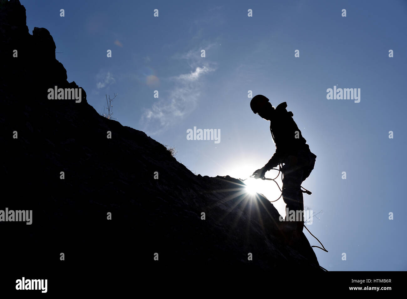 Silhouette di un rocciatore appeso alla parete in modo che il vertice Foto Stock