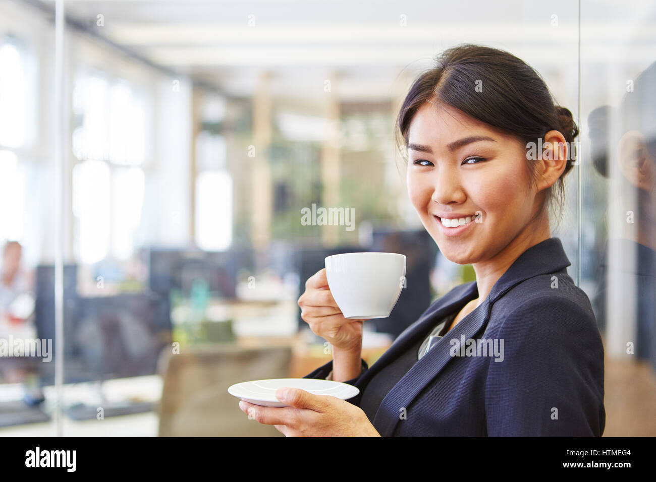 Donna sorridente come imprenditrice prendendo una pausa caffè in ufficio Foto Stock