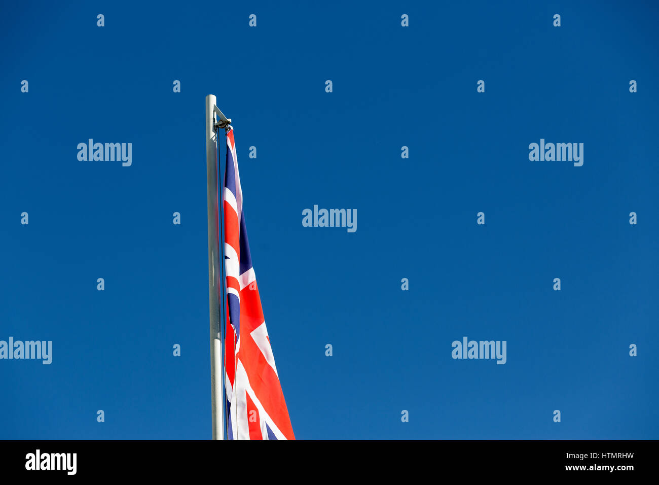 Bandiera del Regno Unito su un pennone di fronte blu cielo Foto Stock