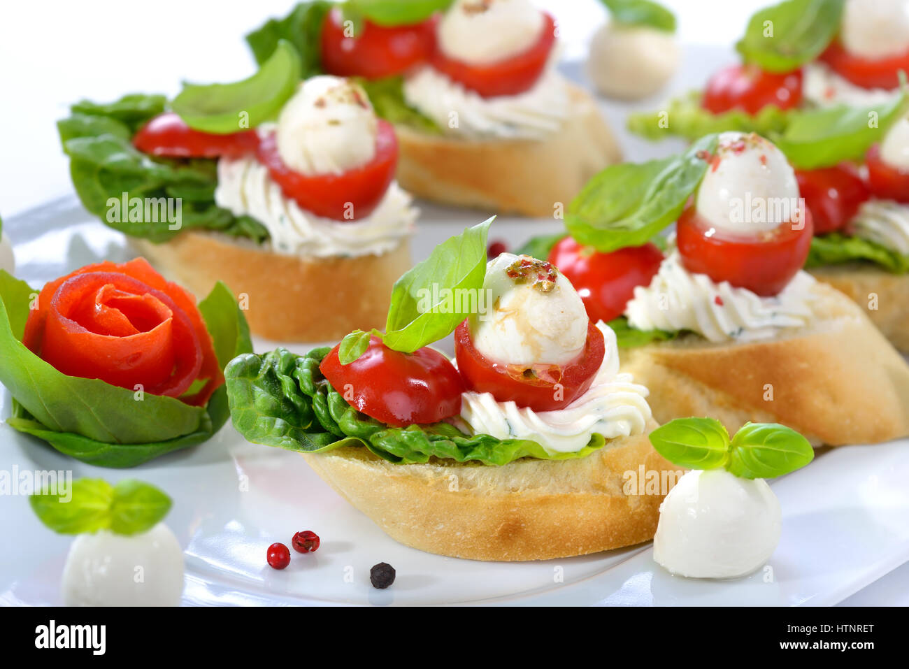 Deliziosi antipasti freddi: fette di baguette con cherry pomodoro, mozzarella, crema di formaggio, olio di oliva e le foglie di basilico Foto Stock