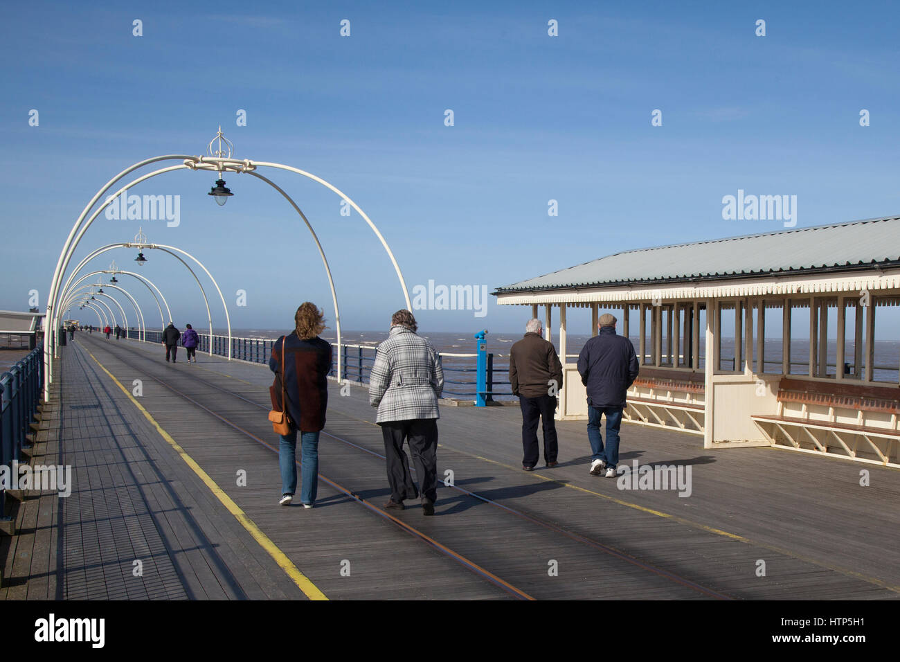 Southport, Merseyside, Regno Unito. Regno Unito Meteo. Il 14 marzo 2017. Luminosa e ariosa con un cielo azzurro per pier passeggini. Barmy marzo temperature continuare nel nord ovest, ma con un po' di più vento rispetto a quella di fine. Le persone sono ben confezionate fino contro la brezza del mare come essi passeggiata verso la fine del 2° molo più lungo in Inghilterra. Credito: MediaWorldImages/Alamy Live News Foto Stock