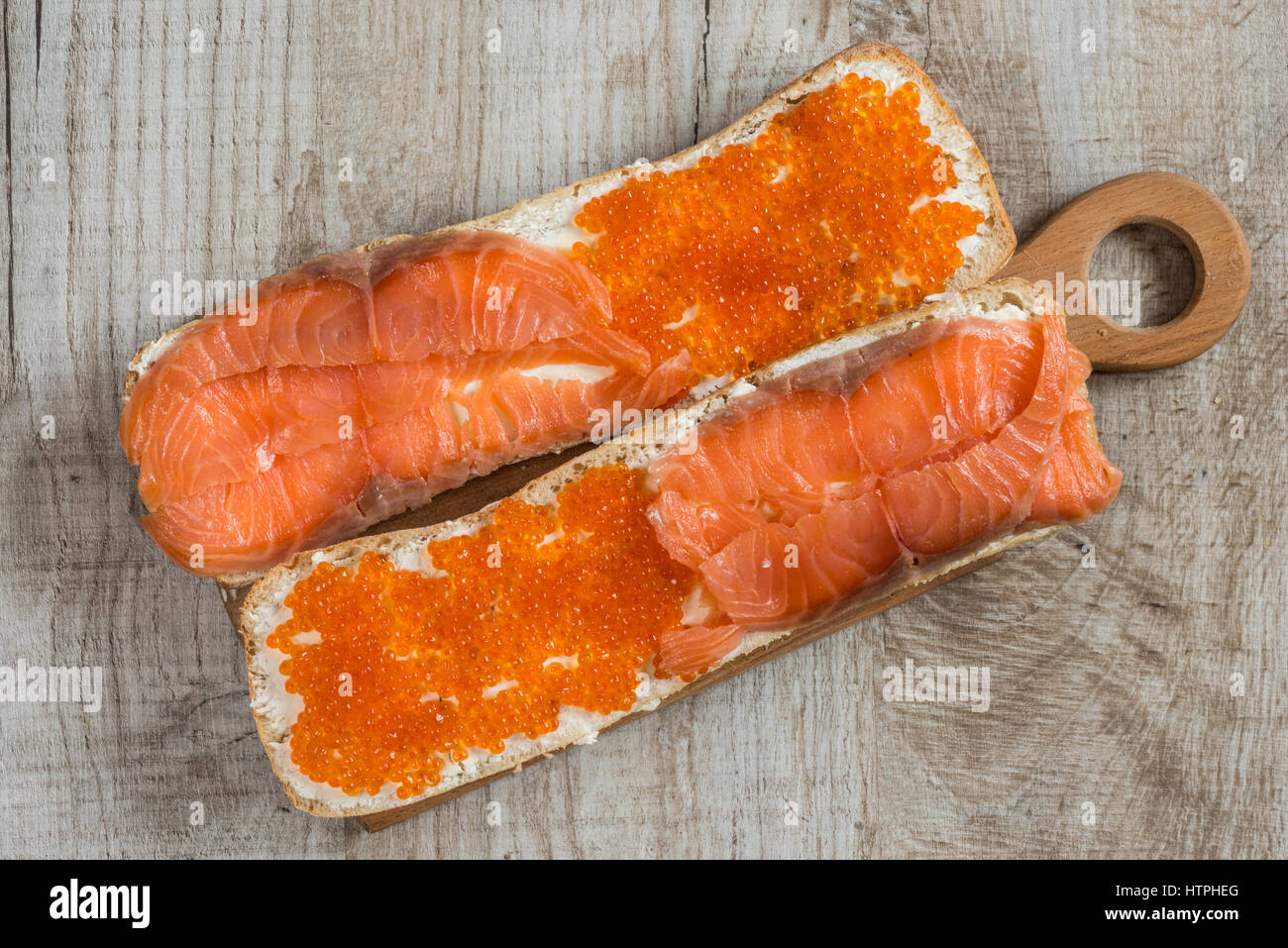 Panini con caviale rosso e salmone su sfondo di legno Foto Stock