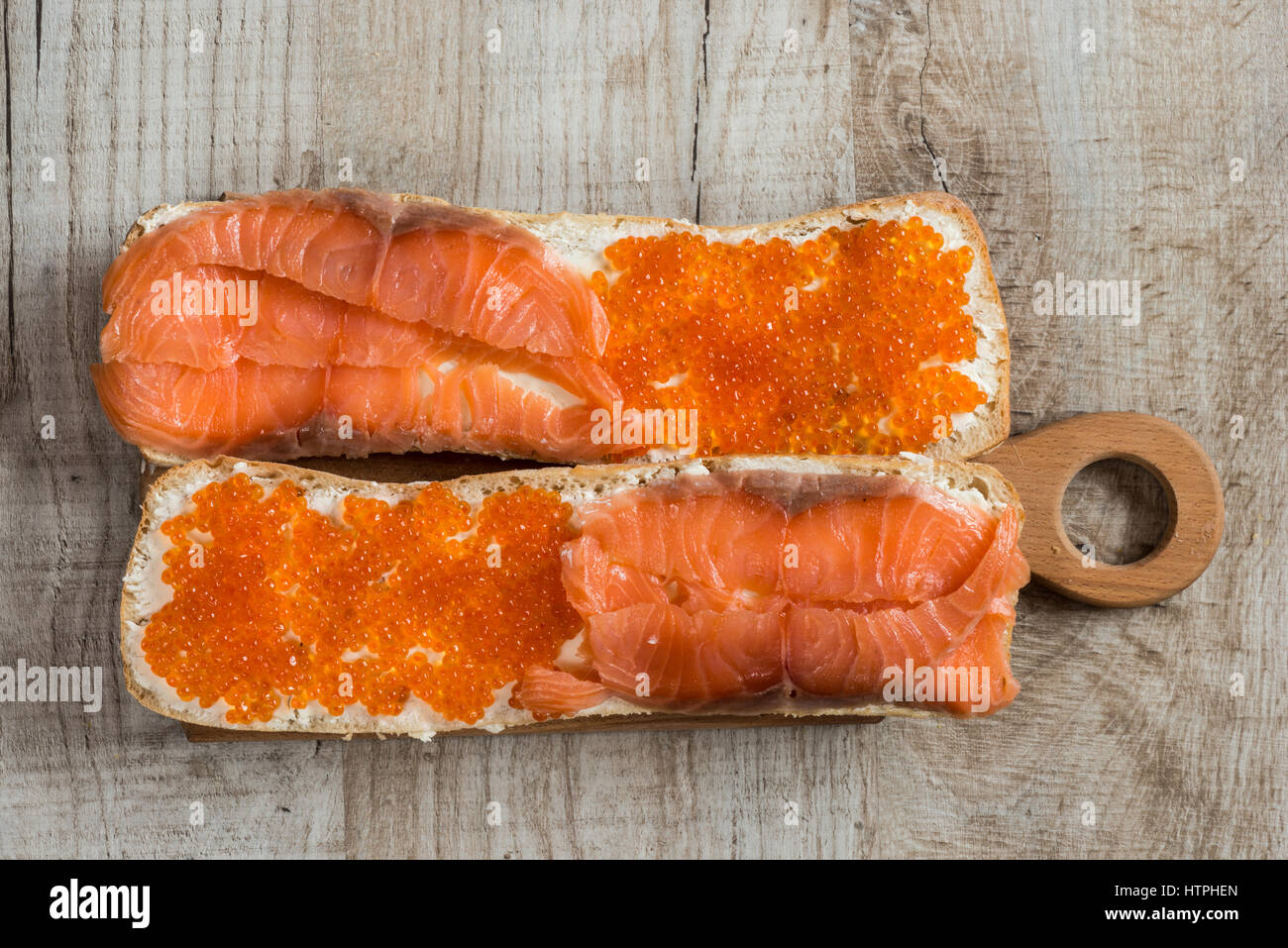 Panini con caviale rosso e salmone su sfondo di legno Foto Stock