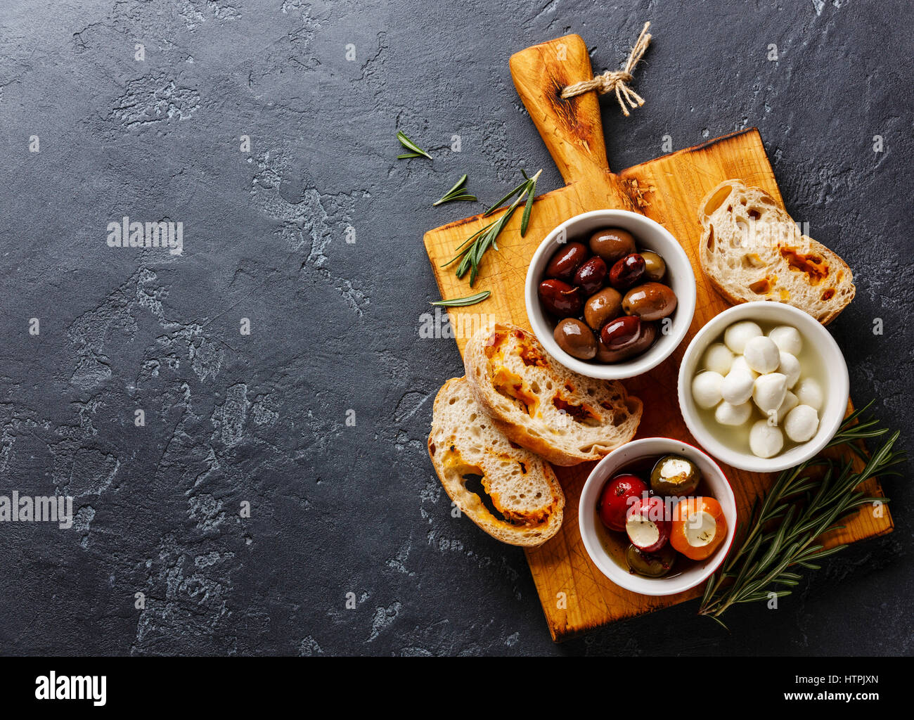 Olive e Peperoni ripieni, mini Mozzarella e fette di pane Ciabatta su sfondo scuro spazio copia Foto Stock