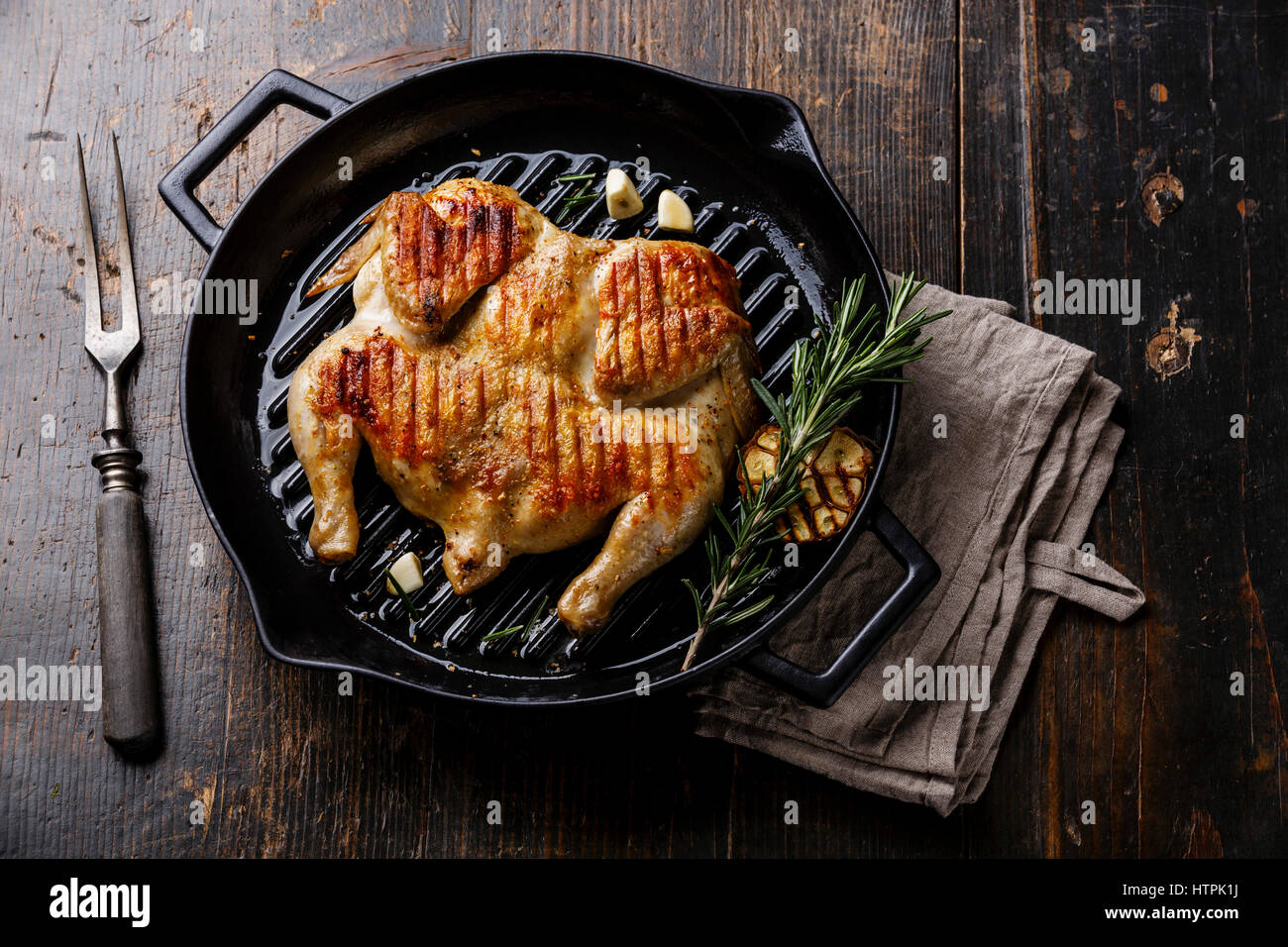 Grigliata di fritto di pollo arrosto Tabaka in padella su sfondo di legno Foto Stock