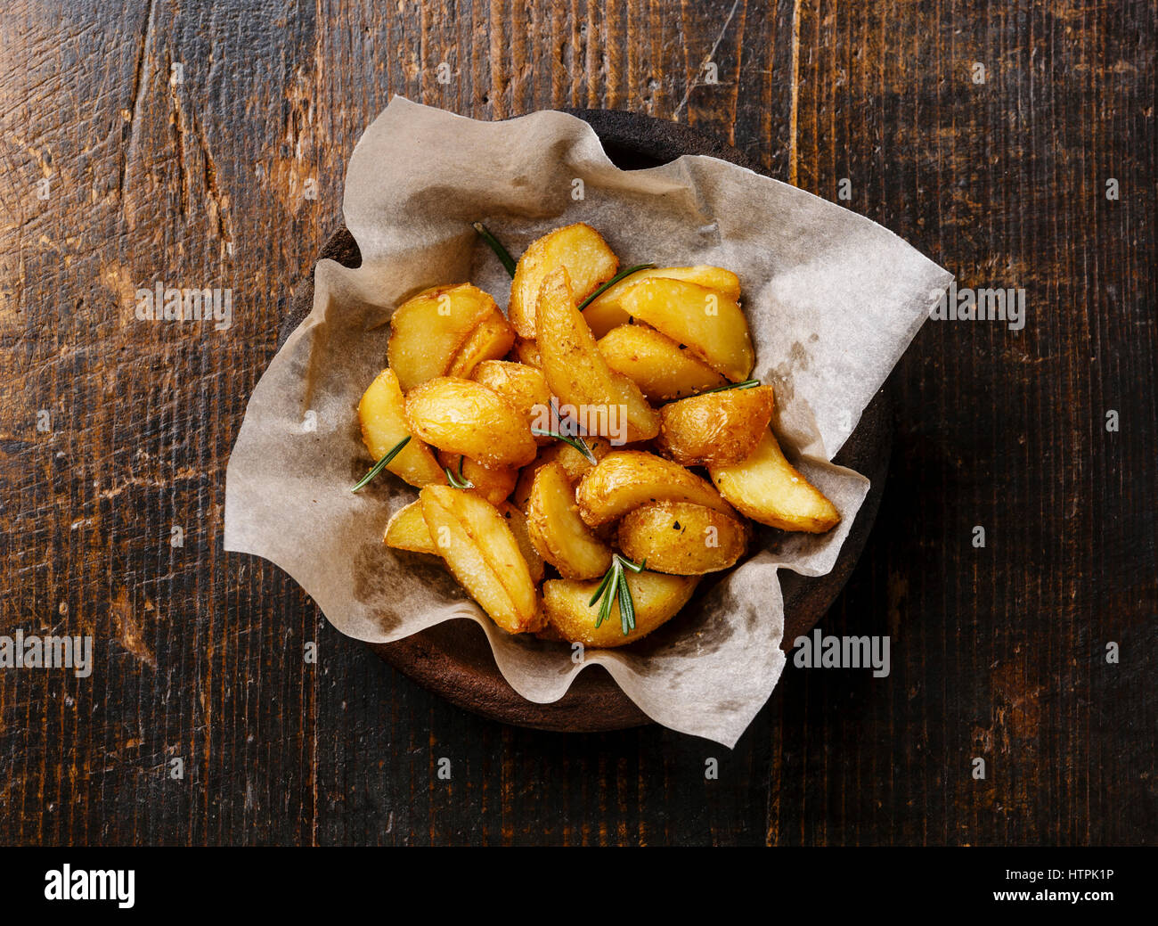 Fritti in stile Country Spicchi di patate su sfondo di legno Foto Stock