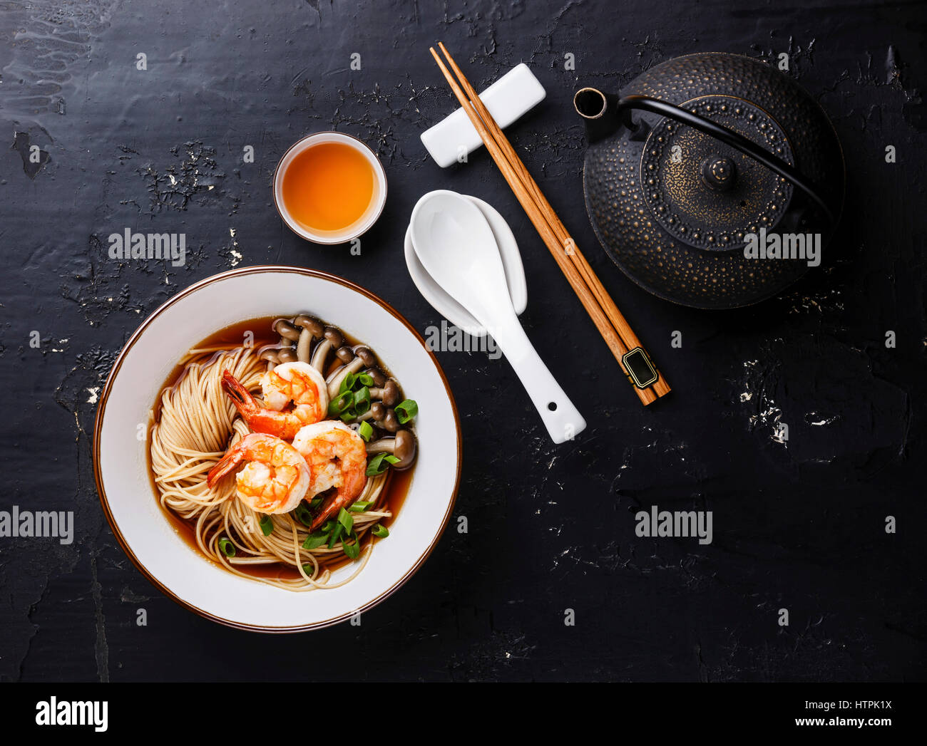 Asian spaghetti ramen con brodo nel recipiente che serve la dimensione e il tè su sfondo scuro Foto Stock
