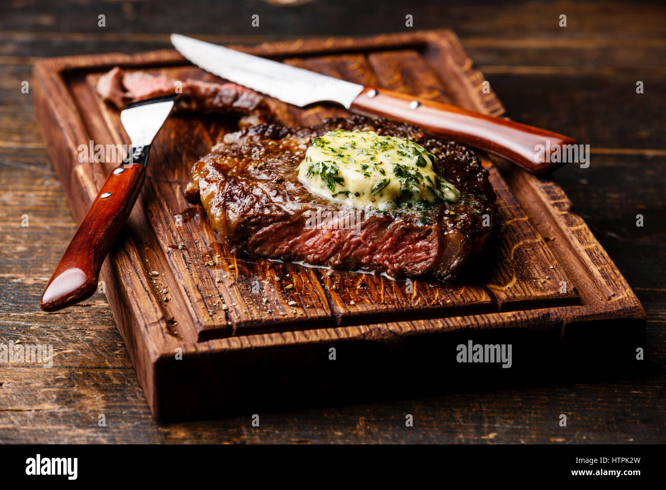 Grigliata di mezzo raro steak bistecca con burro alle erbe sul bordo di taglio serve dimensioni Foto Stock
