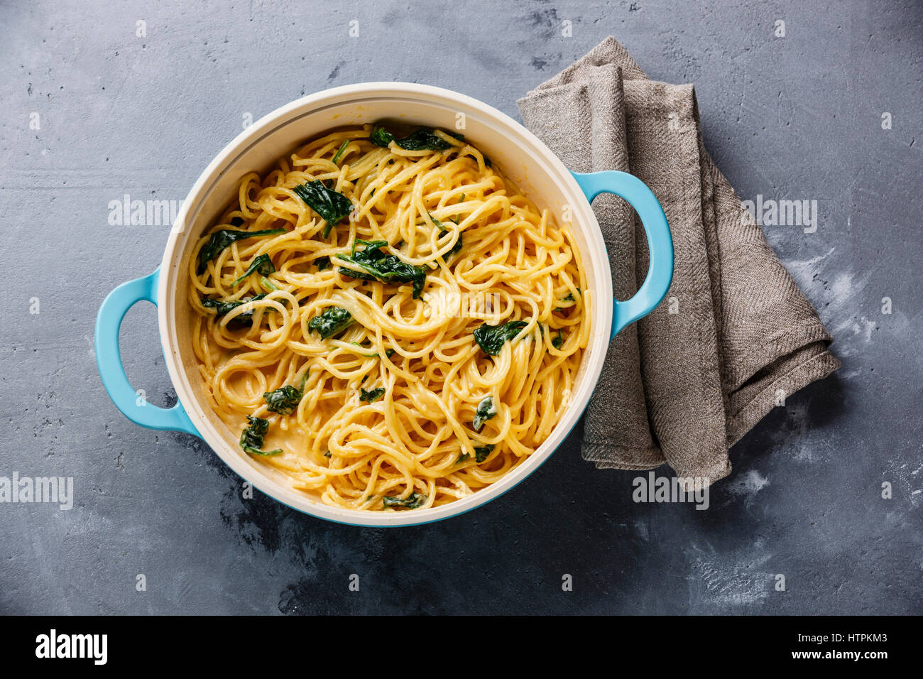 Spaghetti con spinaci e salsa alla panna in padella in grigio sullo sfondo di calcestruzzo Foto Stock