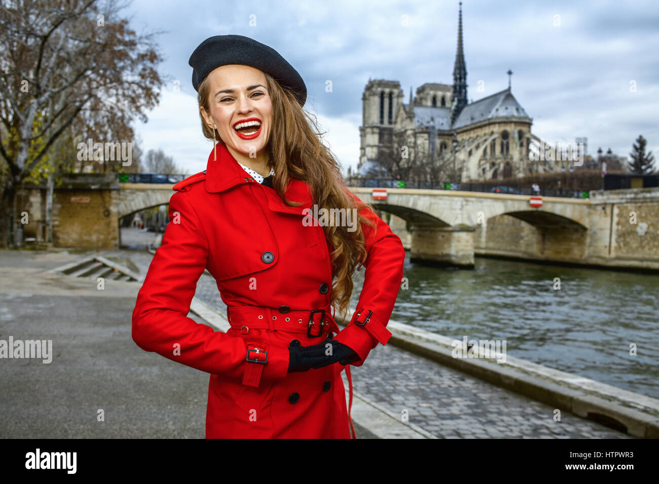 Luminose a Parigi. allegro giovane turista woman in red trench coat sul terrapieno a Parigi, Francia Foto Stock