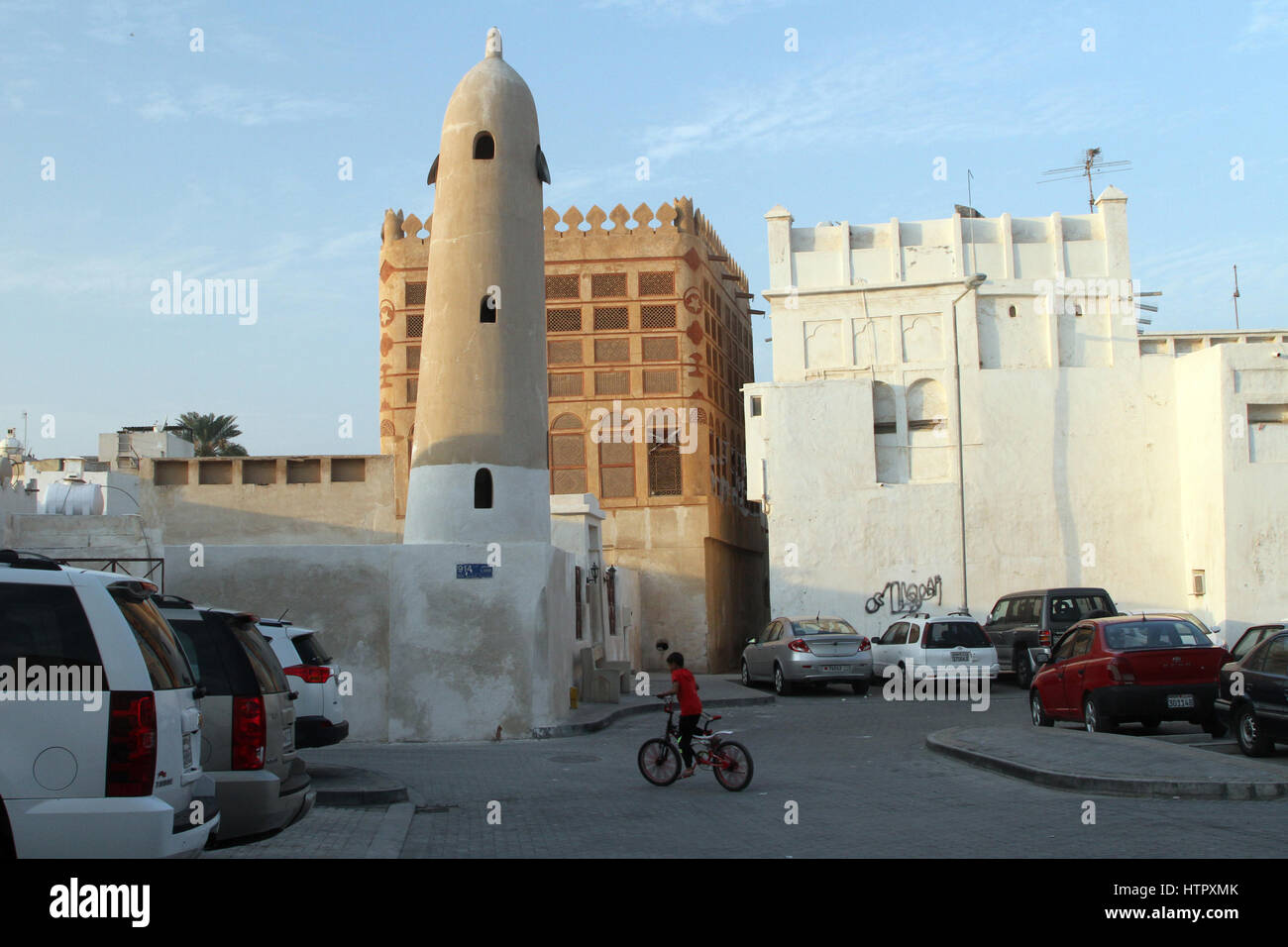 Un bambino vanno in bicicletta attraverso i vicoli di Muharraq, Bahrain Foto Stock