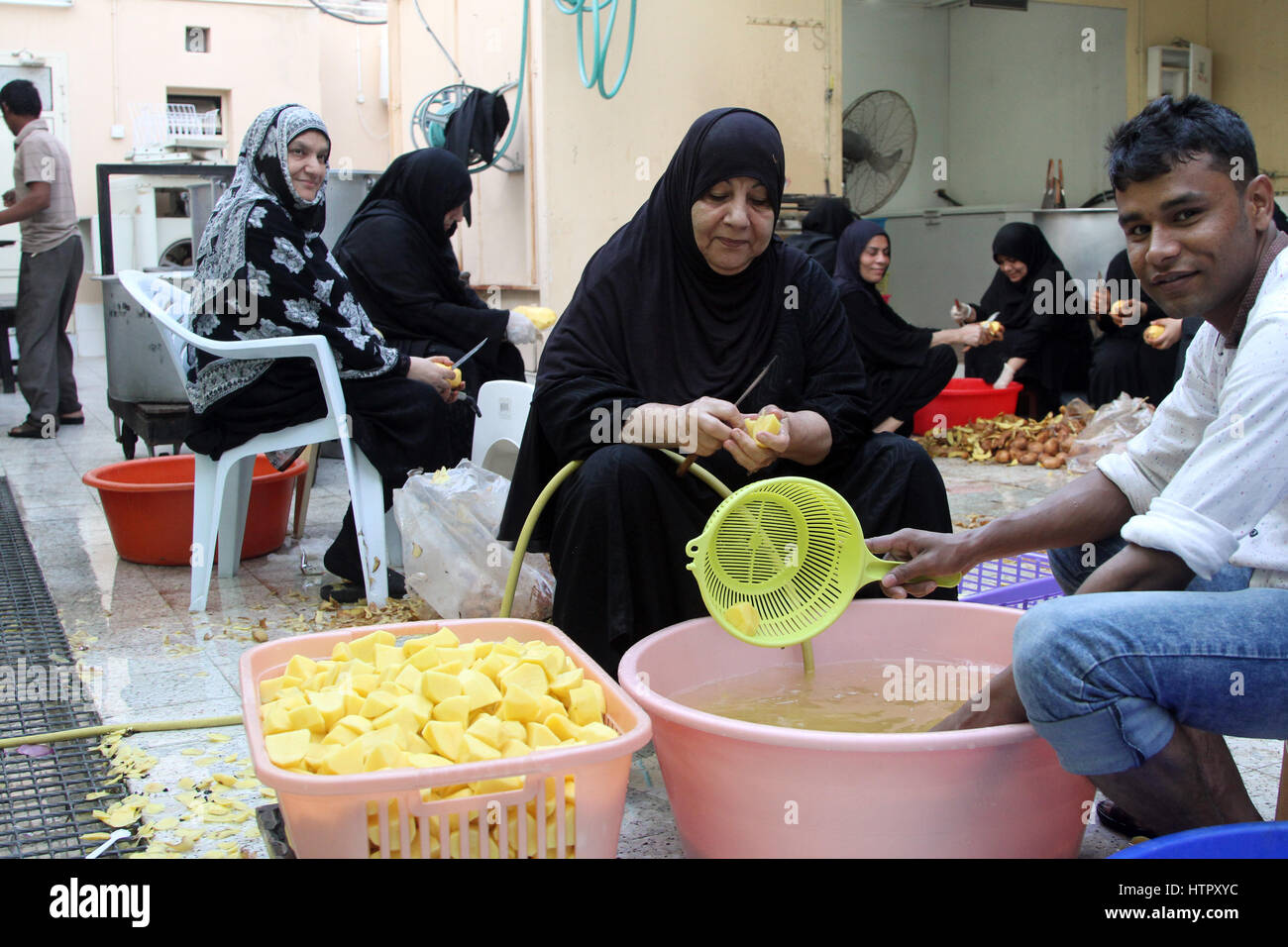 Membri del Bahrain la comunità sciita nella preparazione degli alimenti per un pasto in comune. Foto Stock