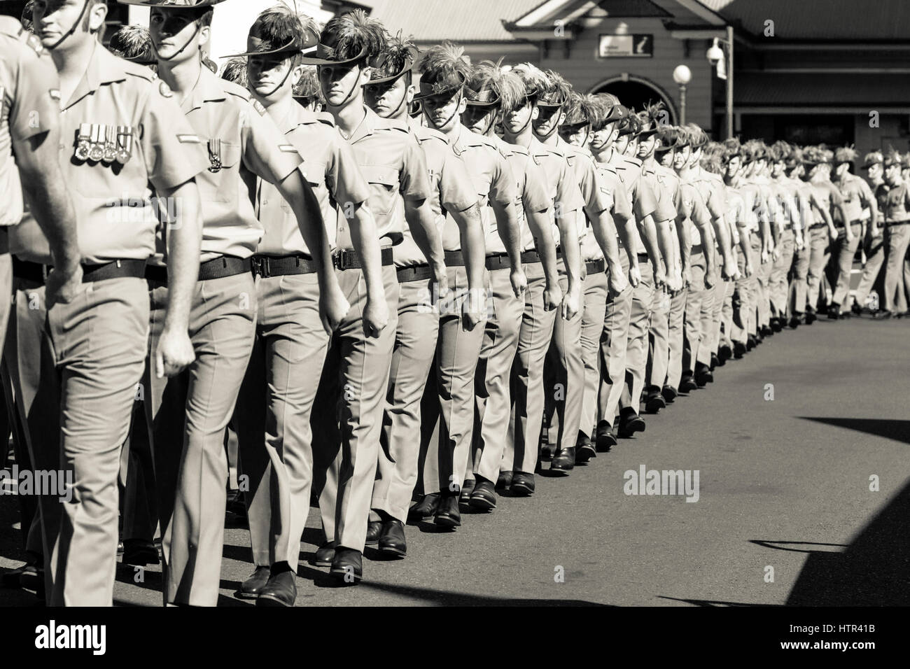 Anzac Day Parade con i soldati che marciano lungo la strada principale di Charters Towers Foto Stock