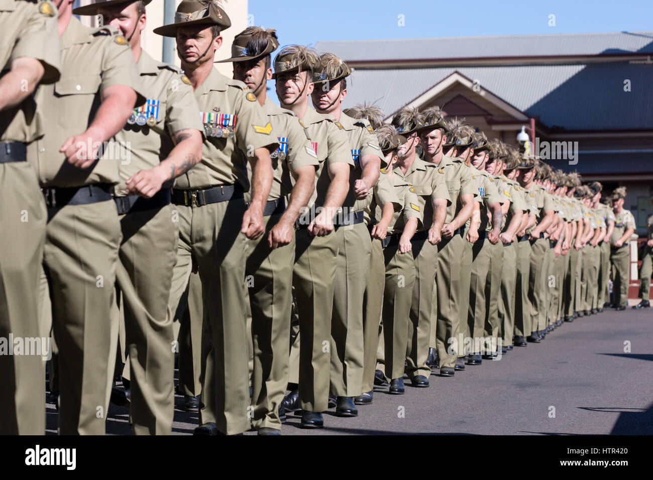 Anzac Day Parade con i soldati che marciano lungo la strada principale di Charters Towers Foto Stock