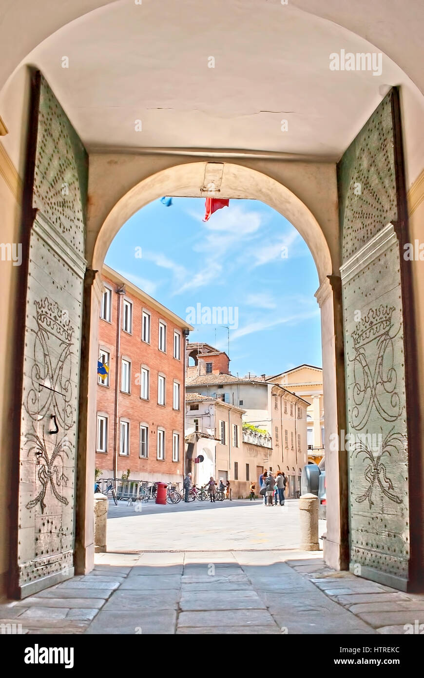 La vista sulla piazza Santafiora attraverso il cancello del Tribunale Amministrativo Regionale della Regione Emilia Romagna, le massicce porte decorate con pattern di Foto Stock