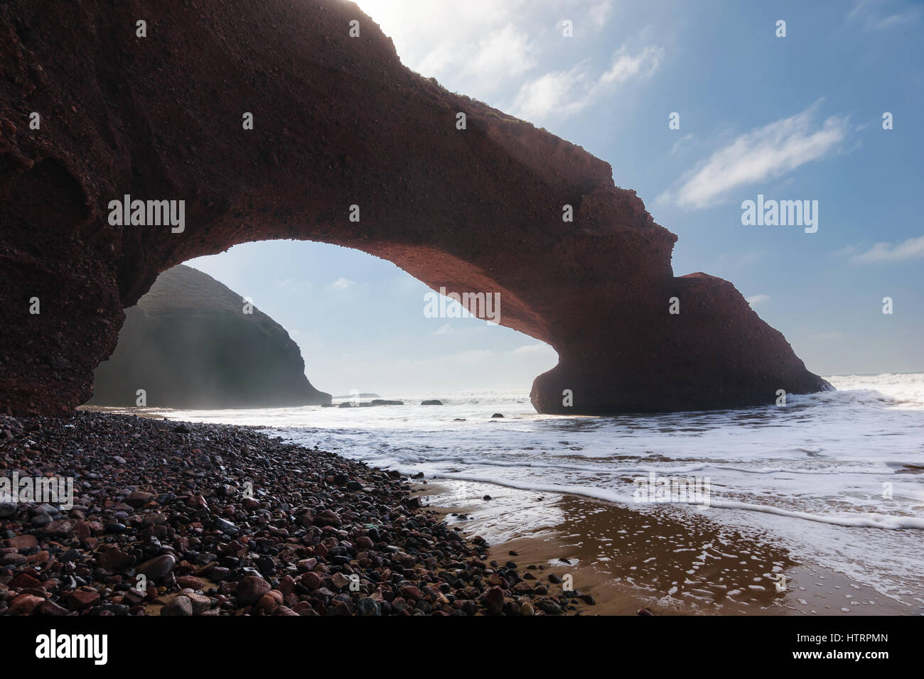 Archi in rosso e la spiaggia rocciosa e all'Oceano Atlantico nella regione Sous-Massa-Draa, Sidi Ifni, Legzira, Marocco, Africa. Foto Stock