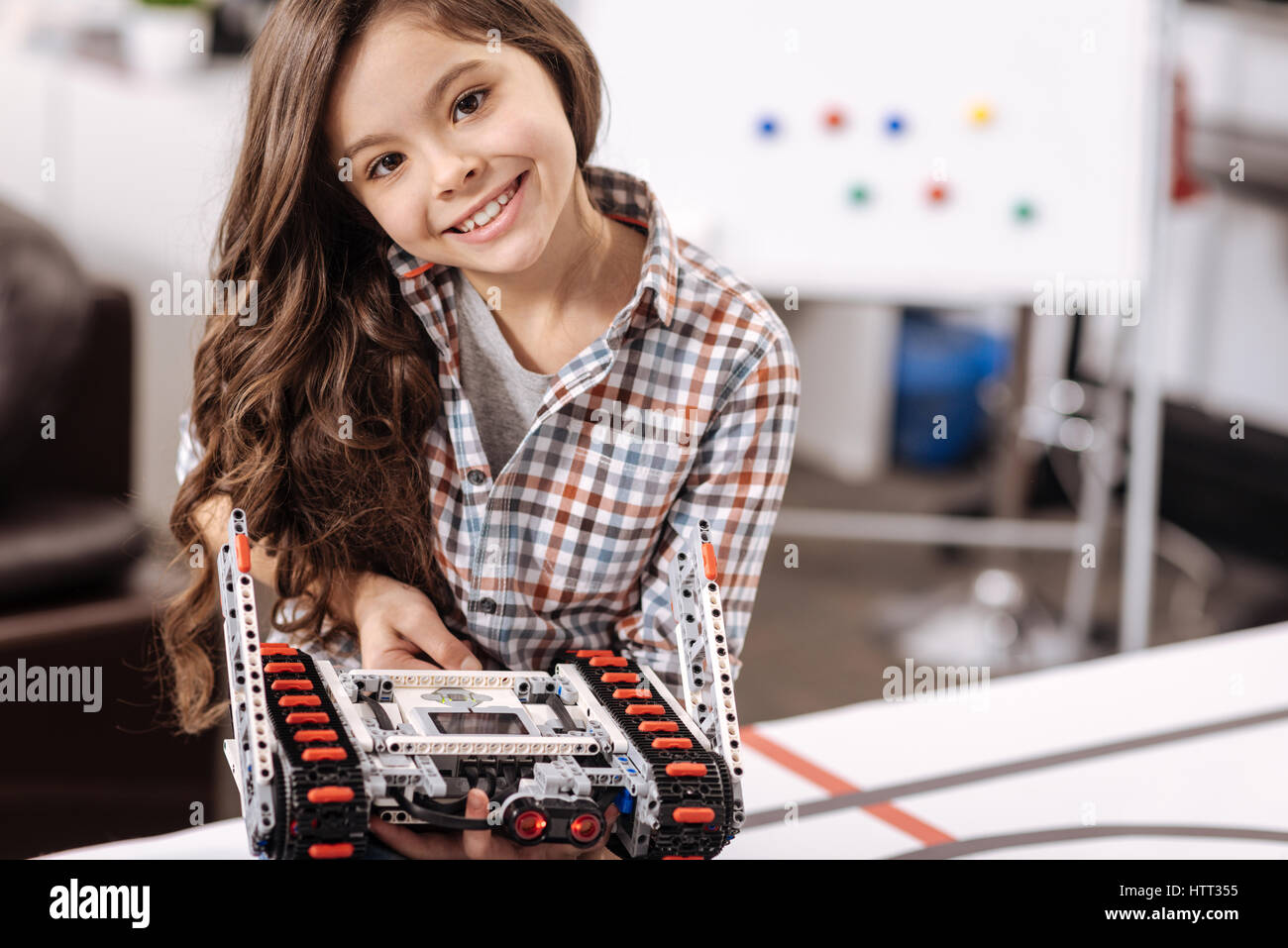 Ragazza sorridente che rappresentano il giocattolo elettronico presso il laboratorio di robotica Foto Stock