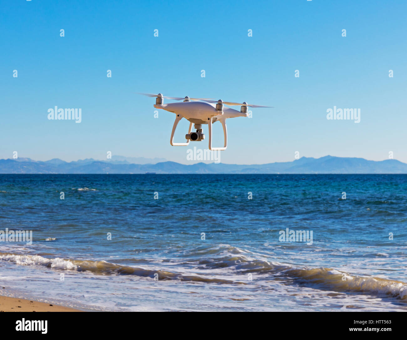 DJI Phantom 4 drone con la fotocamera durante il volo sopra il livello del mare. Costa del Marocco in background. Foto Stock