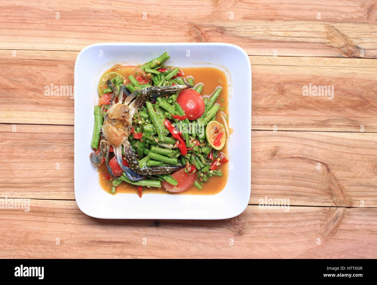 Yardlong insalata di fagioli con il granchio di thai gli alimenti nel piatto bianco su uno sfondo di legno, SOMTUM è il cibo di popolari in Thailandia. Foto Stock