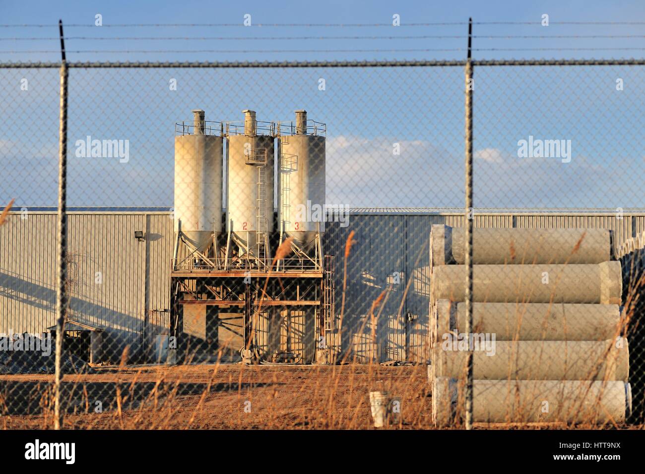 Un azienda di produzione fissato dietro una catena collegamento recinto, sormontato da barb filo in questa impostazione industriale in Bartlett, Illinois.USA. Foto Stock