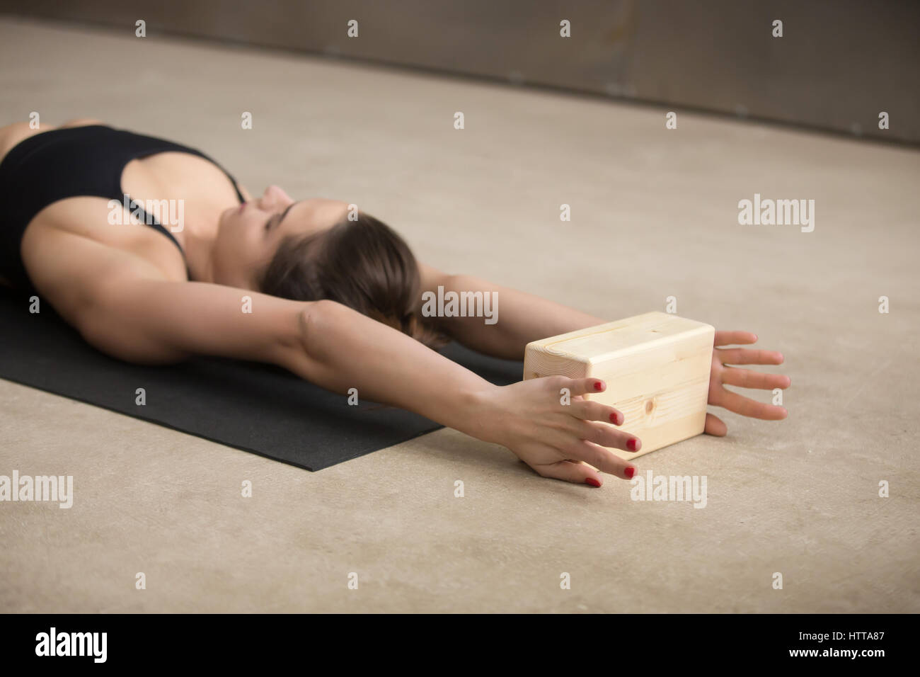 Giovane donna attraente la pratica di Iyengar Yoga con blocco di legno Foto Stock