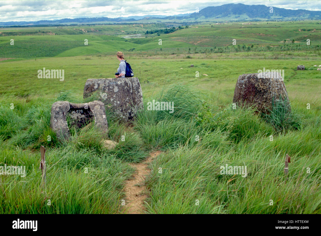 Un turista in mezzo misteriosa pietra urn sulla pianura di giare, un paesaggio segnato dai crateri di bombe e mine inesplose. Xieng Khouang Provincia, Laos Foto Stock