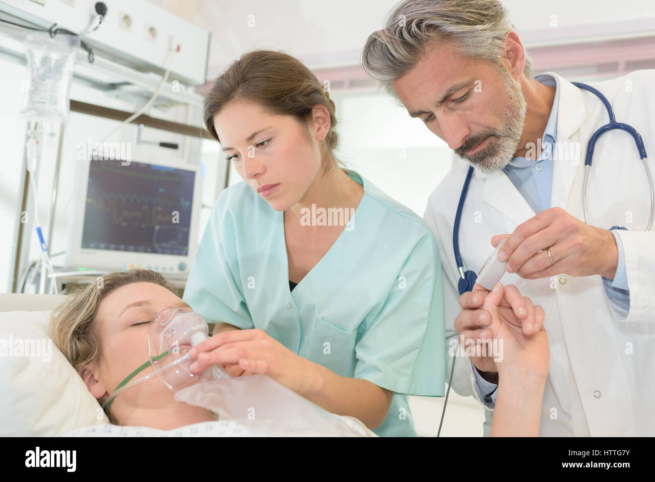 Il personale medico di mettere le maschere di ossigeno e lettore di impulso sul paziente Foto Stock