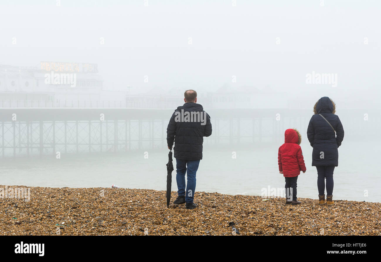 Famiglia su di una spiaggia in riva al mare su un nebbioso giorno in Brighton, East Sussex, Inghilterra, Regno Unito. Foto Stock