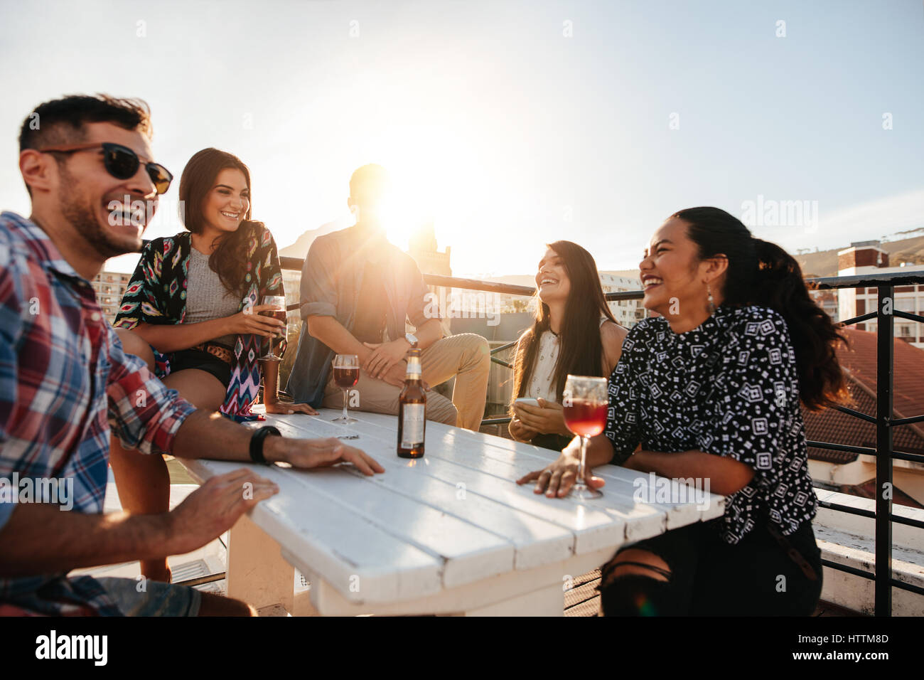 Colpo all'aperto di felice giovani avente una parte sul tetto. Gli amici di ridere e godendo di partito. Foto Stock Colpo all'aperto di felice giovani avente una parte sul tetto. Gli amici di ridere e godendo di partito. Foto Stock