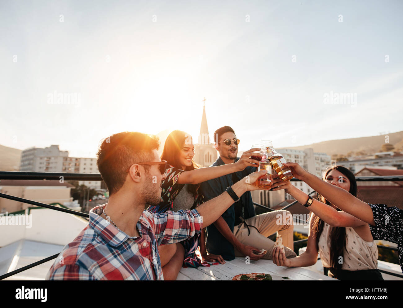 Giovani amici appendere fuori con un drink sulla terrazza sul tetto. I giovani a parte le birre di tostatura. Foto Stock Giovani amici appendere fuori con un drink sulla terrazza sul tetto. I giovani a parte le birre di tostatura. Foto Stock