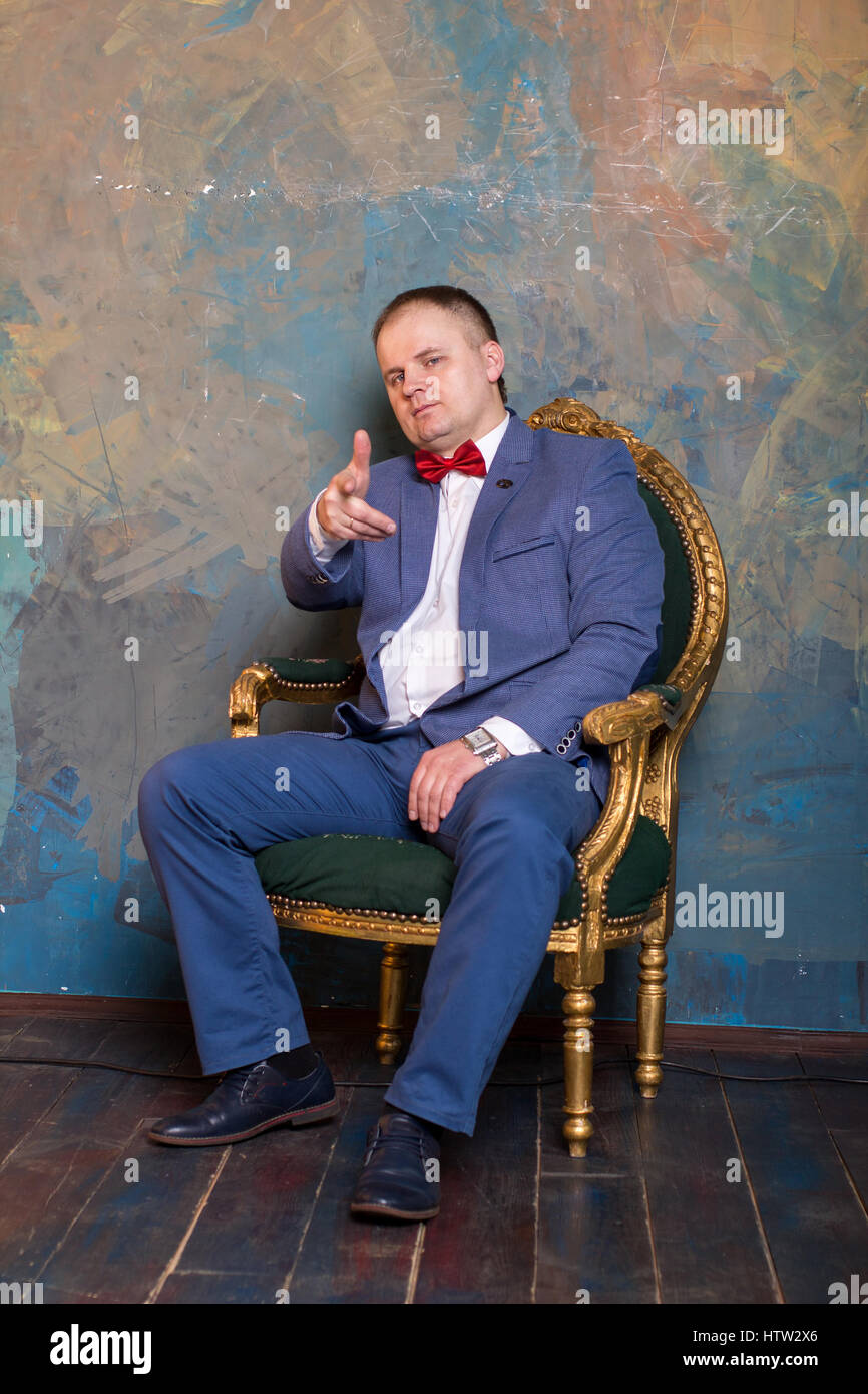 Imponente uomo maturo in elegante abito seduto su una sedia in pelle in un  moderno e lussuoso degli interni. Moda. Azienda Foto stock - Alamy