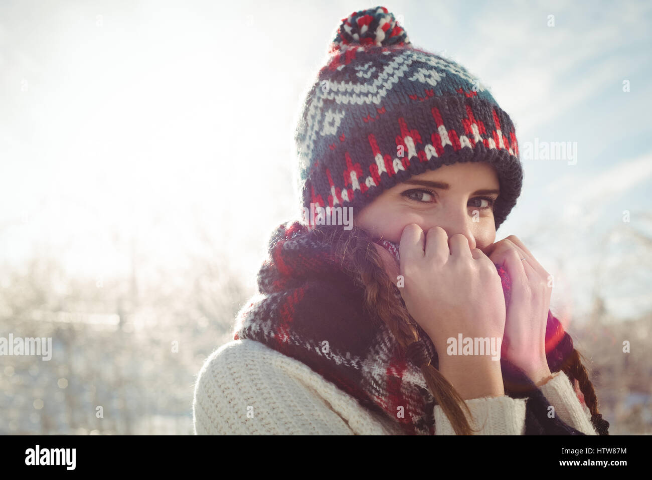 Bella donna in abiti caldi che copre la bocca con il ponticello Foto Stock