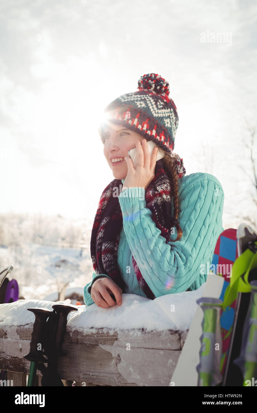 Donna in inverno indossare parlando al telefono contro la luce diretta del sole Foto Stock