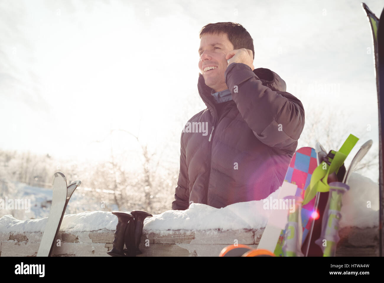 Uomo in inverno indossare parlando al telefono contro la luce diretta del sole Foto Stock
