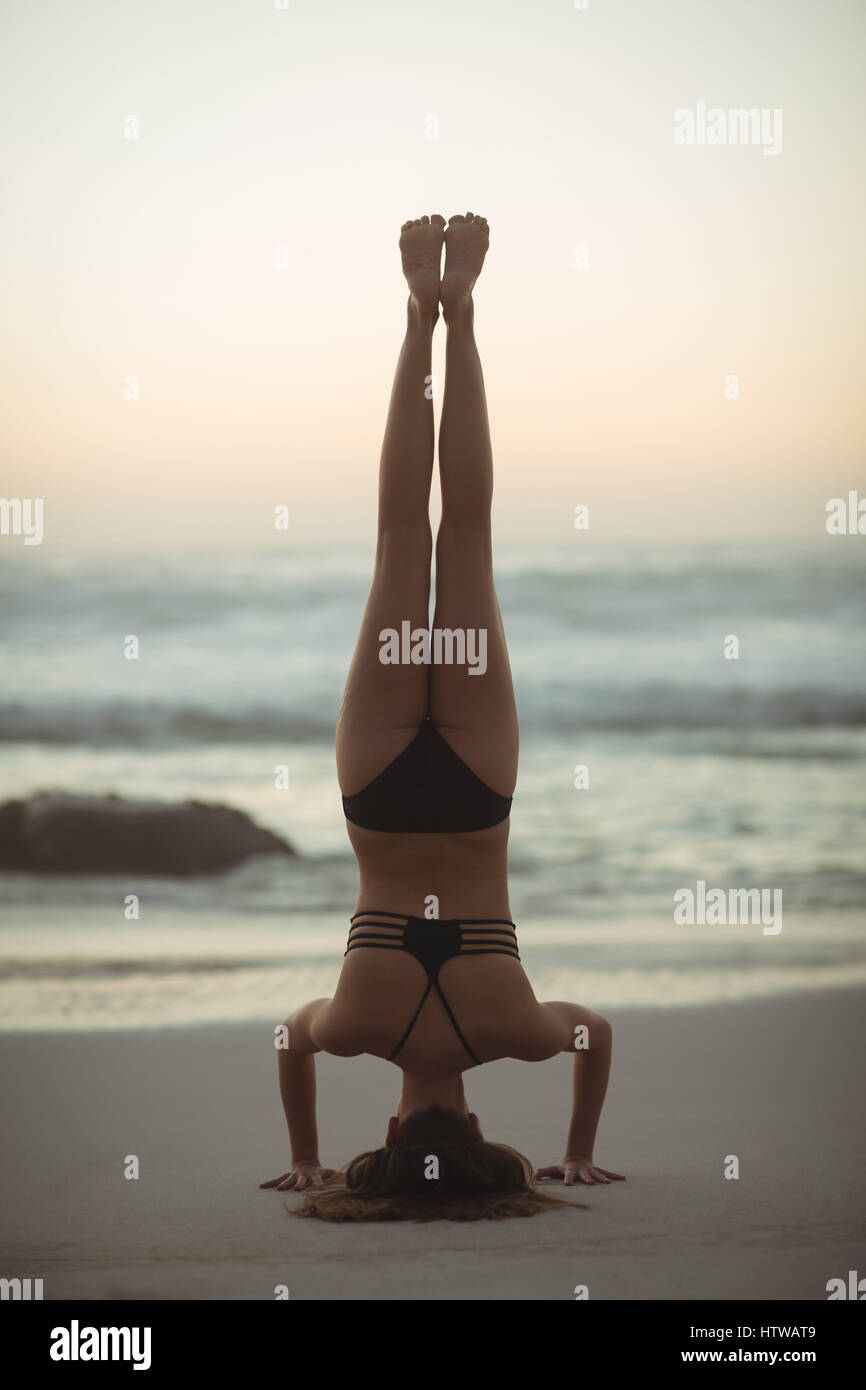 Donna di eseguire headstand sulla spiaggia Foto Stock