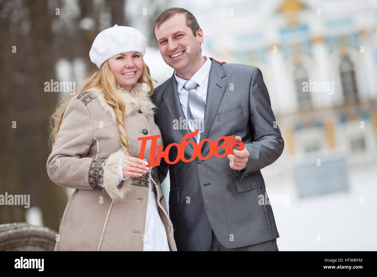 Ritratto di giovane attraente sposa giovane azienda in mani la parola russa di amore. In inverno il parco innevato Foto Stock
