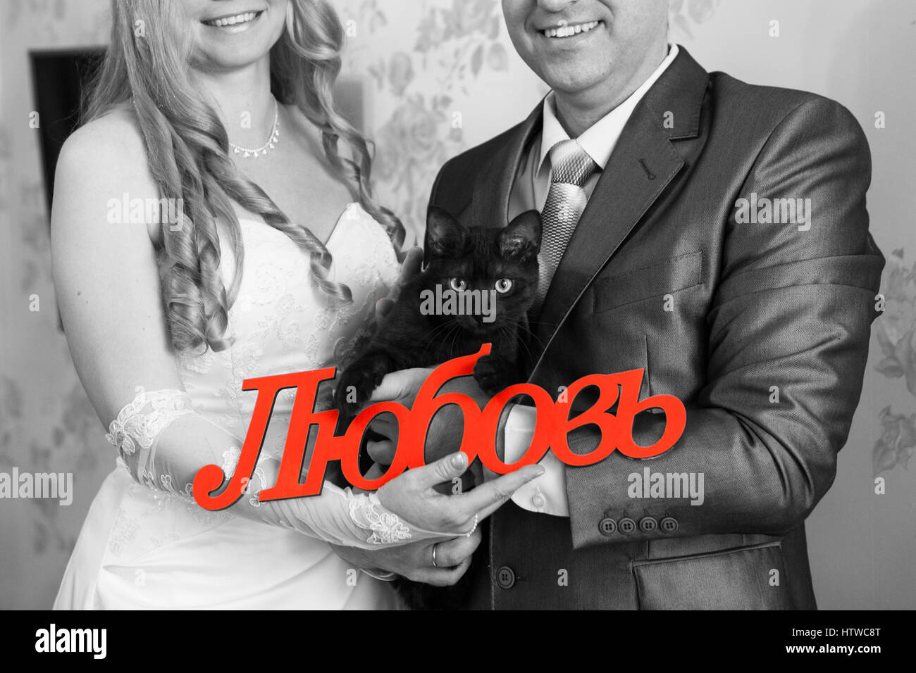 Gatto nero e la parola amore in russo nelle mani della sposa e lo sposo, immagine in bianco e nero con rosso iscrizione Foto Stock