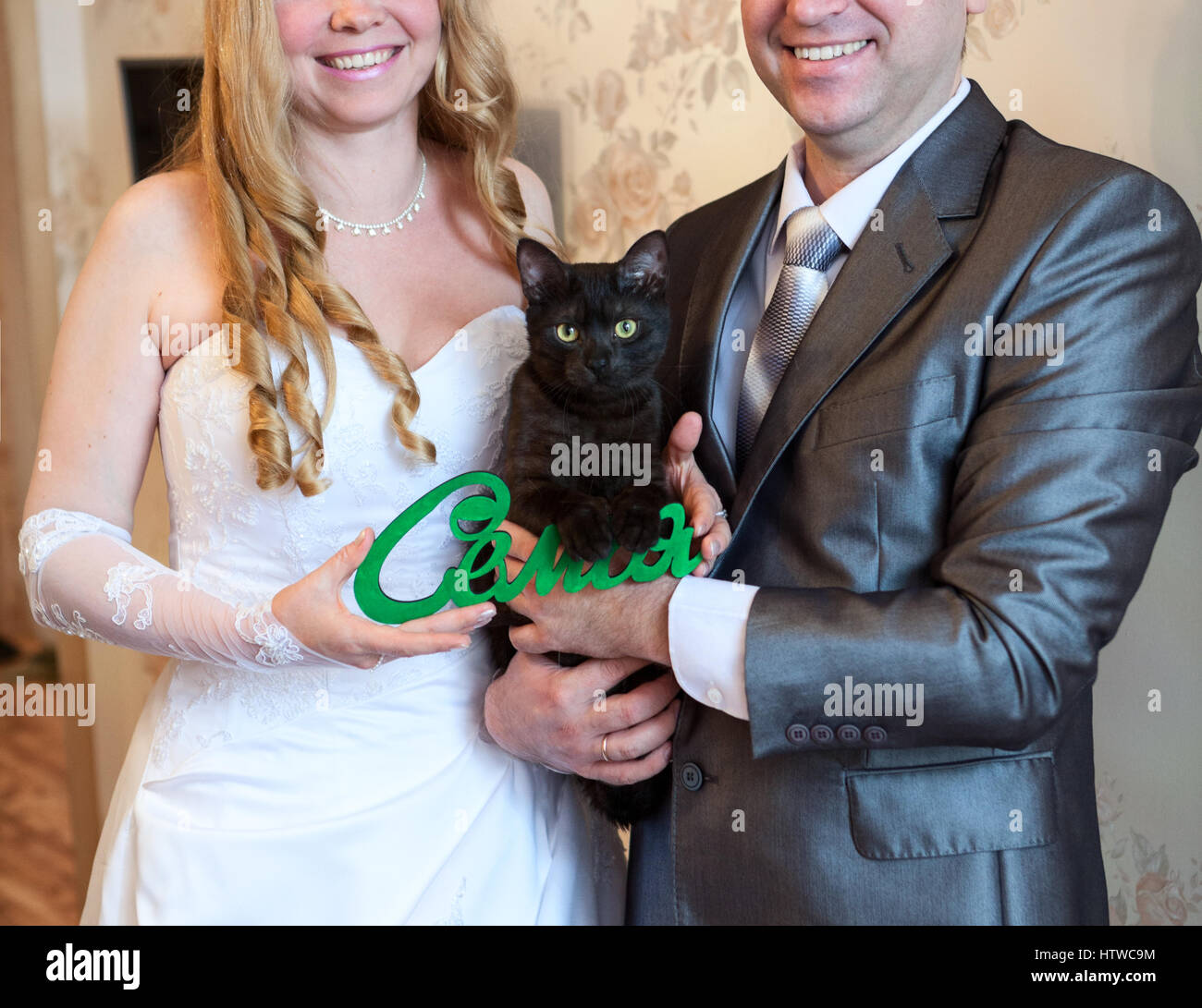 Gatto nero seduti sulle mani di sposa giovane, parola famiglia in russo Foto Stock