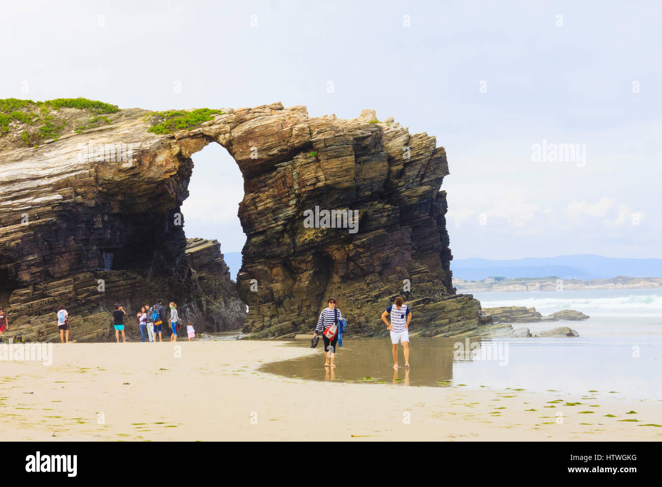I turisti da un arco in pietra presso la spiaggia delle cattedrali monumento naturale a ribadeo comune, provincia di Lugo, Galizia, Spagna, Europa Foto Stock